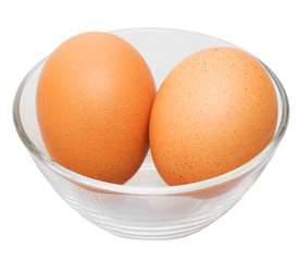 Two brown eggs in glass bowl