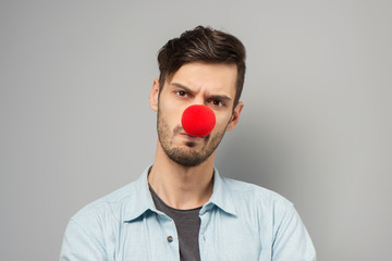 Sad young man with clown nose