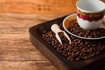 Fototapeta na wymiar Cup with plate on tray full of coffee beans