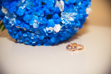 wedding rings on a white background with a bouquet of blue ribbo