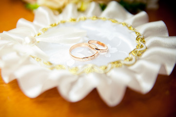 Two gold wedding rings lying on the white pillow