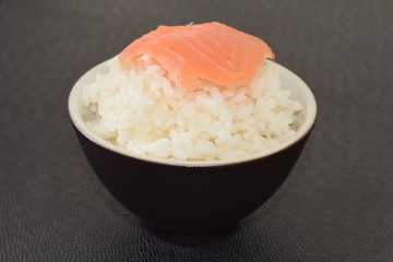 Sushi with salmon in a bowl on a black background.
