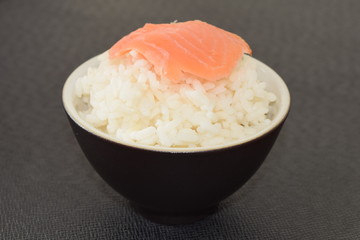 Sushi with salmon in a bowl on a black background.