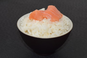 Sushi with salmon in a bowl on a black background.
