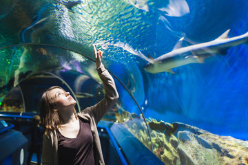 Young girl in aquarium tunnel with sharks - Powered by Adobe