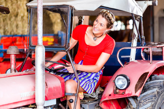 B&auml;urin mit Dirndl f&auml;hrt Trecker