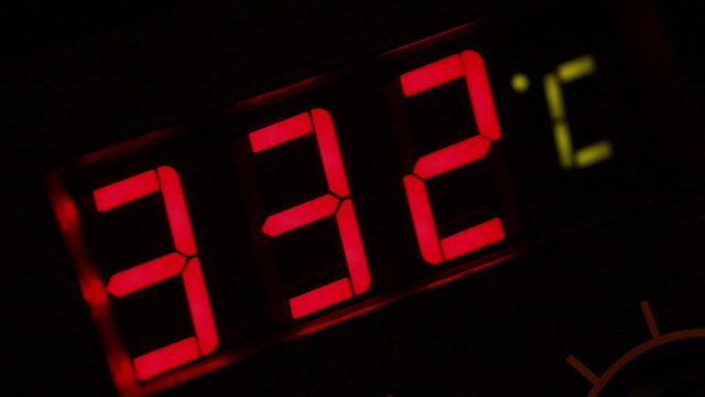 Thermometer with red digits shows the temperature rise