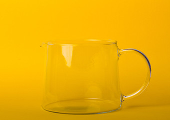 Glass teapot on a yellow background