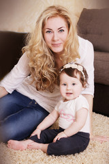 Mother and baby girl sitting and playing on carpet