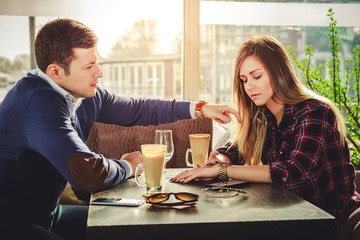 Girl is looking at watch while he is touching her hair