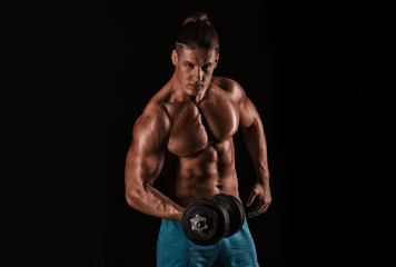 Fototapeta na wymiar Strong athletic man with perfect body posing with dumbbells