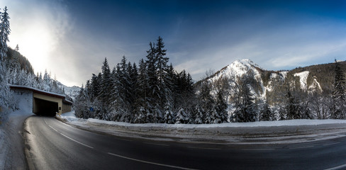 panoramic shot of highway in snowy mountains with long turn