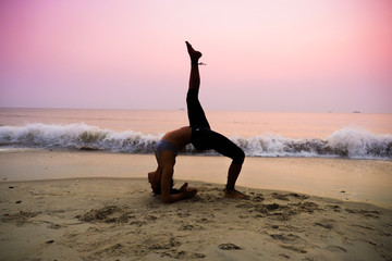 Fototapeta na wymiar silhouette of woman practicing yoga on the beach sunrise