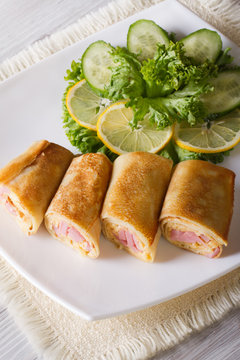 Crepes filled ham and cheese on a white plate. vertical