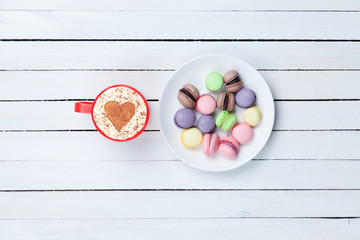 Cappuccino with heart shape symbol and macaron
