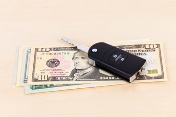 Modern car key and dollar banknote on white background