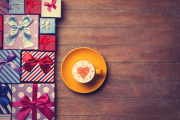 Cup and gift boxes on wooden background