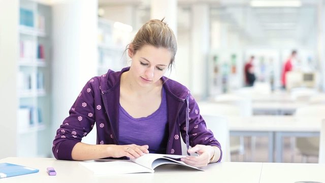 Pretty young female college student in a modern library