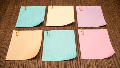 Six colorful post-it notes on wooden background.