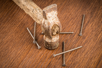 Old hammer with nails on the wooden background.