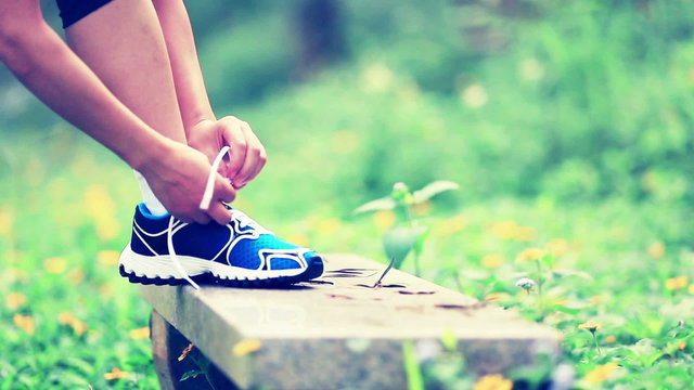 woman runner tying shoelace in the nature