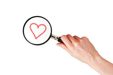 Magnifier glass in woman hand and red heart isolated on white