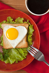 Fried heart shaped egg on toast with salad and coffee for Valent