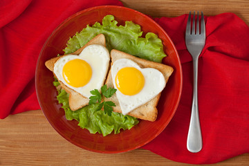 Two fried heart shaped eggs on toast with salad and coffee for V