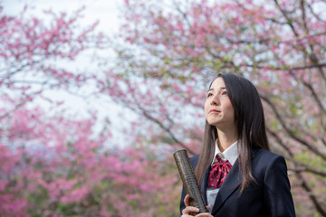 卒業証書の筒を持って笑っている女子学生