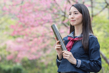 卒業証書の筒を持って笑っている女子学生