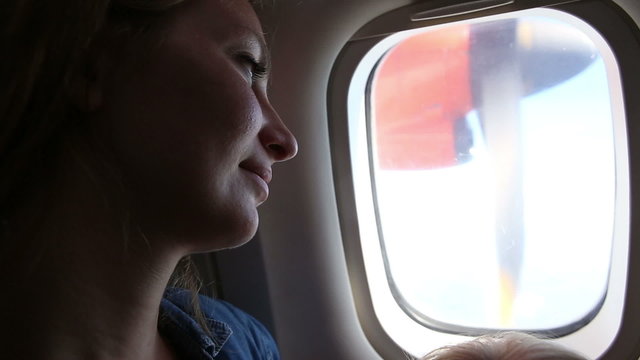 woman smile and looks out of plane window	