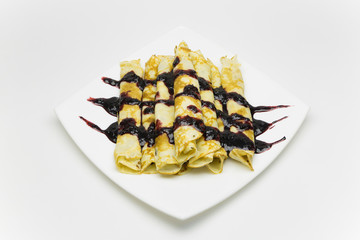 Russian pancakes of golden colour on a white plate watered with