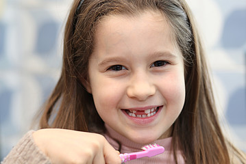 young girl without a tooth while brushing teeth