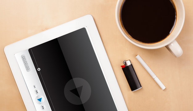 Tablet pc showing media player on screen with a cup of coffee on