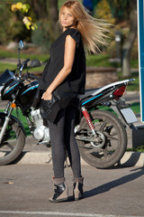 Fototapeta na wymiar Pretty woman is standing near motorcycle
