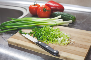 Chopped green onions and vegetables on striped wooden board