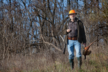 Elderly hunter with wildfowl in orange hat