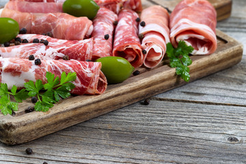 Various raw meats on serving board with rustic background