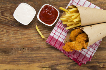 Nuggets and chips served in a paper bag with a dip