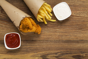 Nuggets and chips served in a paper bag with a dip