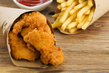 Nuggets and chips served in a paper bag with a dip
