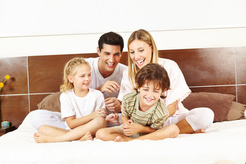 Lachende Familie sitzt im Bett