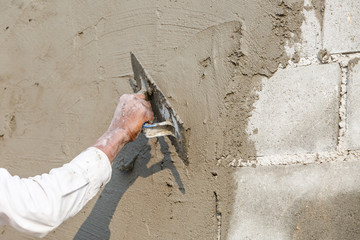 plasterer concrete worker at wall of house construction