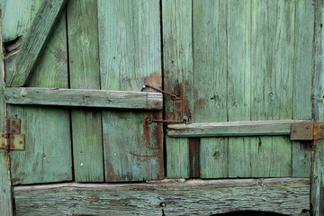 The old green shutters of window with metallic hooks