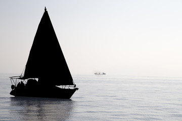 Sailboat silhouette at the sea in a foggy day. Yachting tourism