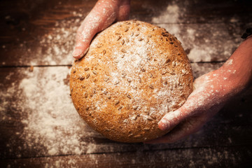 Baker hands with fresh bread on table