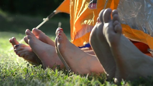 Legs of two young couples acting funny in tent.