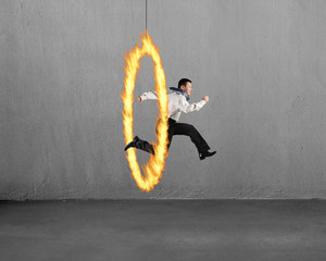 Man jumping through fire hoop with concrete wall