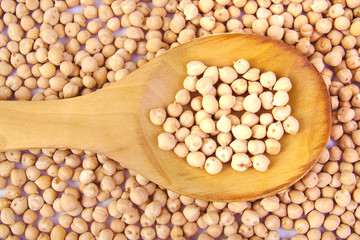 Uncooked chickpeas on wooden spoon