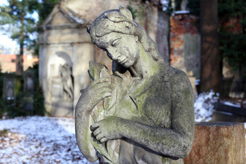 Fototapeta na wymiar Stone Girl on Tomb from snowy old Prague Cemetery
